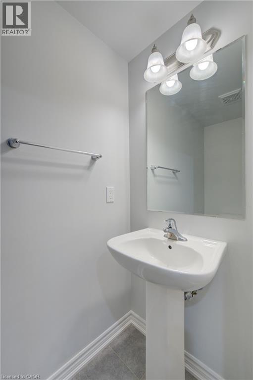Pedestal sink with chrome faucet, large vanity mirror, and three-bulb vanity light fixture - 911 Apple Hill Lane, Kitchener, ON - Indoor Photo Showing Bathroom
