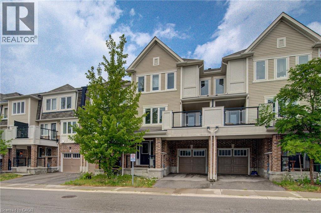 Contemporary townhome exterior featuring light-colored siding, brick accents, multiple balconies with glass railings, and individual garage access - 911 Apple Hill Lane, Kitchener, ON - Outdoor With Balcony With Facade