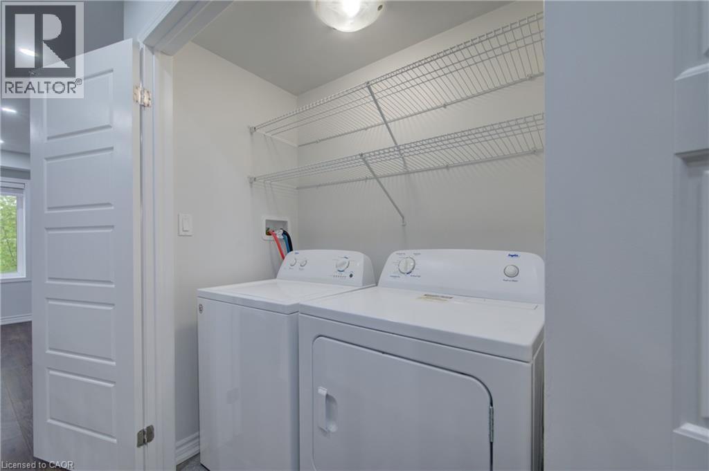 Dedicated laundry area featuring a white top-load washer, a white front-load dryer, and two levels of wire shelving - 911 Apple Hill Lane, Kitchener, ON - Indoor Photo Showing Laundry Room