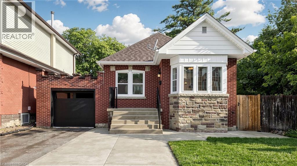 Brick exterior featuring a stone accent bay window with white trim, a concrete driveway, and an integrated single-car garage with a modern black door - 59 Longwood Road N, Hamilton, ON - Outdoor