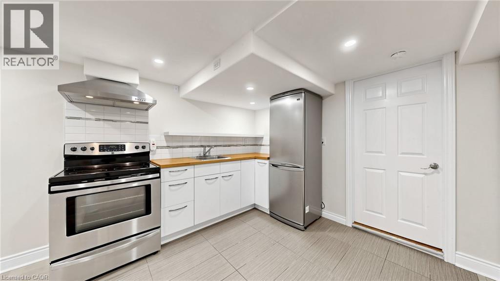 Compact kitchen featuring stainless steel appliances, including a range and refrigerator - 59 Longwood Road N, Hamilton, ON - Indoor Photo Showing Kitchen With Stainless Steel Kitchen