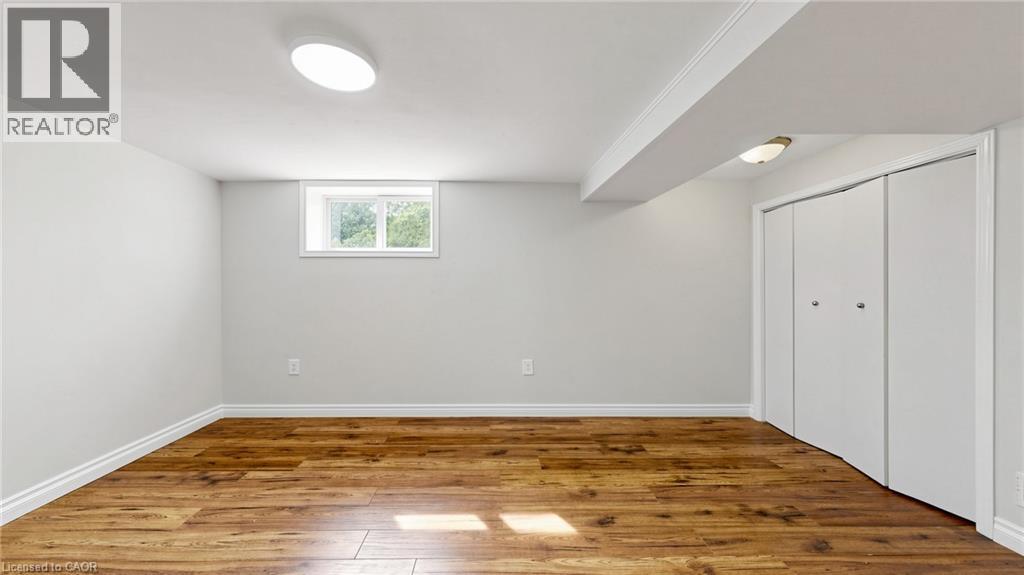 Finished room featuring wood-finish flooring, a window, white walls, and bi-fold closet doors - 59 Longwood Road N, Hamilton, ON - Indoor Photo Showing Other Room