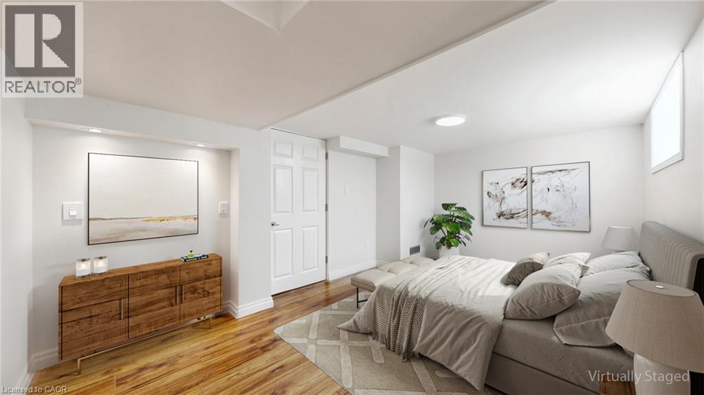 Bright interior space featuring wood-finish flooring, white walls, and a white paneled door - 59 Longwood Road N, Hamilton, ON - Indoor Photo Showing Bedroom