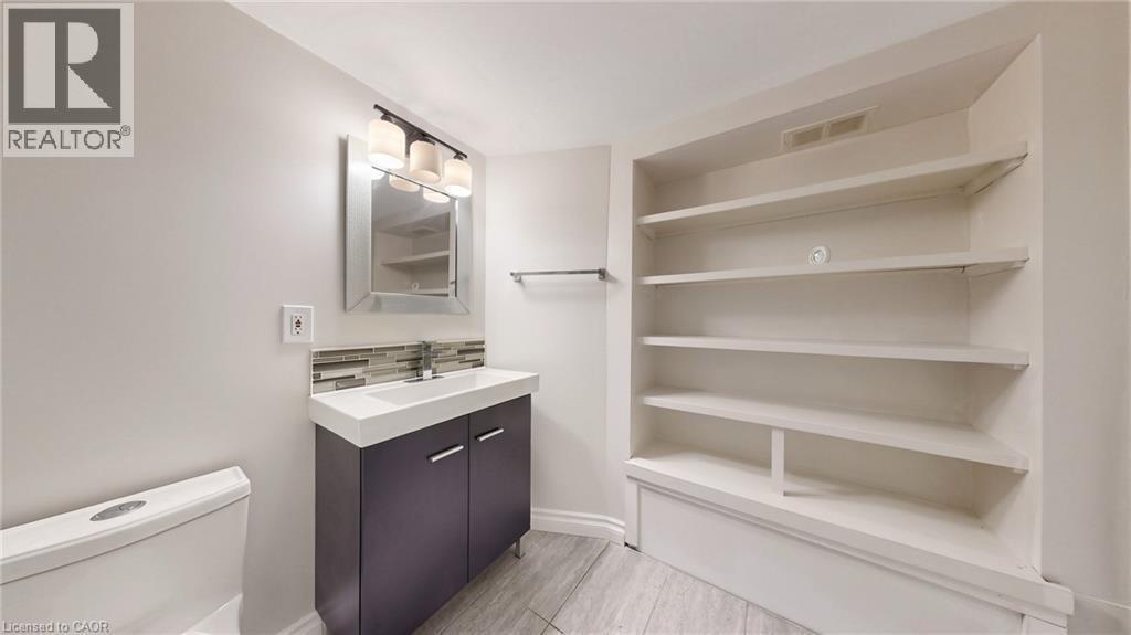 Modern vanity with a rectangular basin, chrome faucet, and glass tile backsplash - 59 Longwood Road N, Hamilton, ON - Indoor With Storage