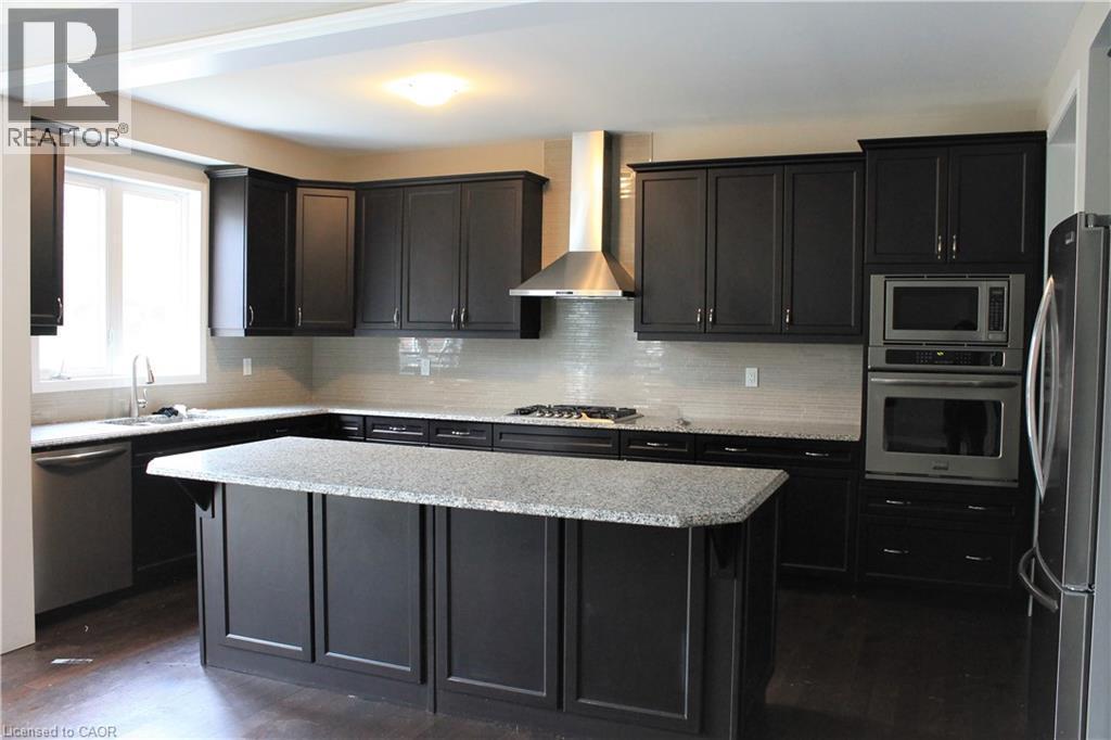 Modern kitchen featuring dark wood-finish cabinetry, light-toned countertops, a full suite of stainless steel appliances, a tiled backsplash, and recessed lighting - 31 Pointer Street Unit# Main Floor, Cambridge, ON - Indoor Photo Showing Kitchen With Double Sink