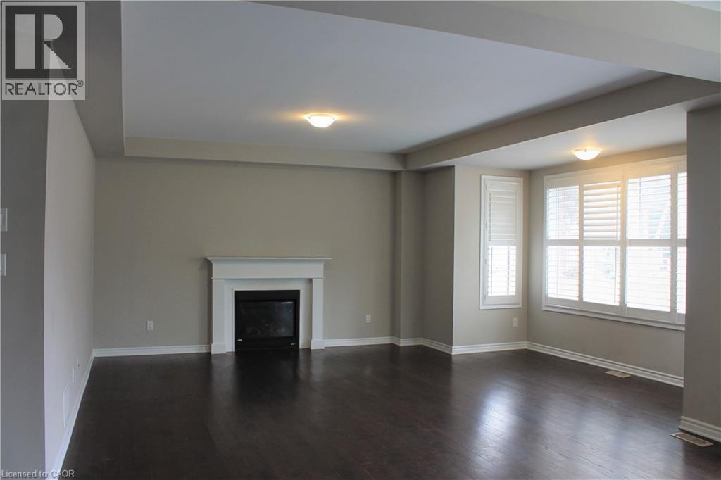 Spacious room featuring dark wood-finish flooring, a white mantel fireplace, and multiple windows with plantation shutters - 31 Pointer Street Unit# Main Floor, Cambridge, ON - Indoor With Fireplace