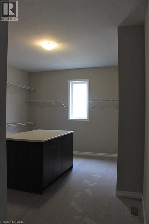Spacious walk-in closet featuring a central island with dark cabinetry and a light-colored countertop - 31 Pointer Street Unit# Main Floor, Cambridge, ON - Indoor