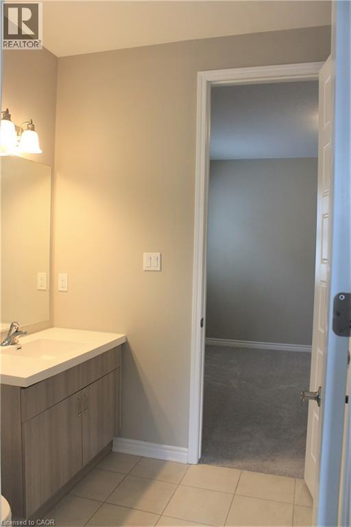 Bathroom vanity featuring a light wood-finish cabinet with double doors, an integrated countertop sink, and a mirrored backsplash - 31 Pointer Street Unit# Main Floor, Cambridge, ON - Indoor Photo Showing Bathroom