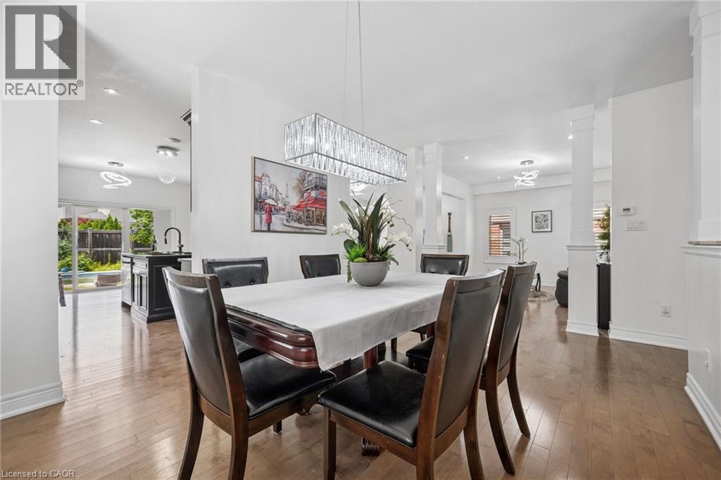 Dining area featuring wood-finish flooring and a linear crystal chandelier - 145 Redtail Street, Kitchener, ON - Indoor Photo Showing Dining Room