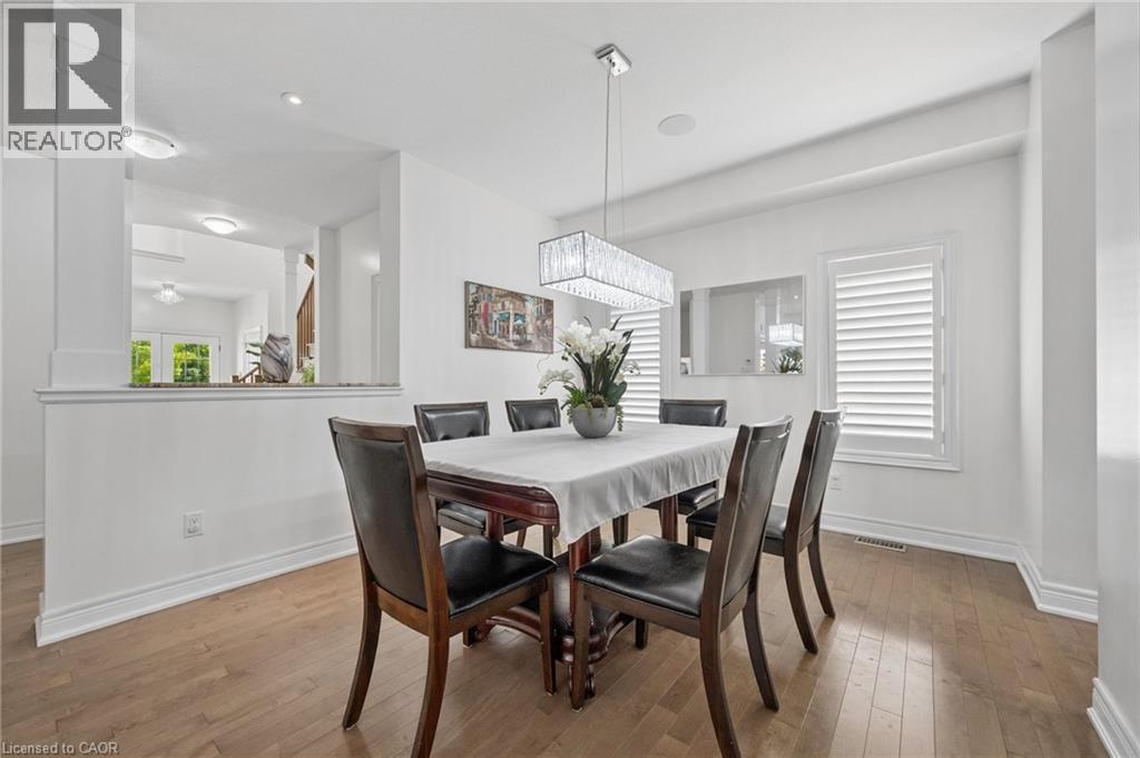 Dining area featuring wood-finish flooring, white walls, and a crystal chandelier - 145 Redtail Street, Kitchener, ON - Indoor Photo Showing Dining Room