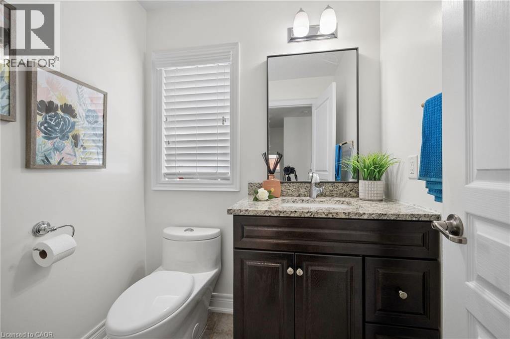 Powder room featuring a dark wood-finish vanity with a granite countertop, undermount sink, and a rectangular mirror - 145 Redtail Street, Kitchener, ON - Indoor Photo Showing Bathroom