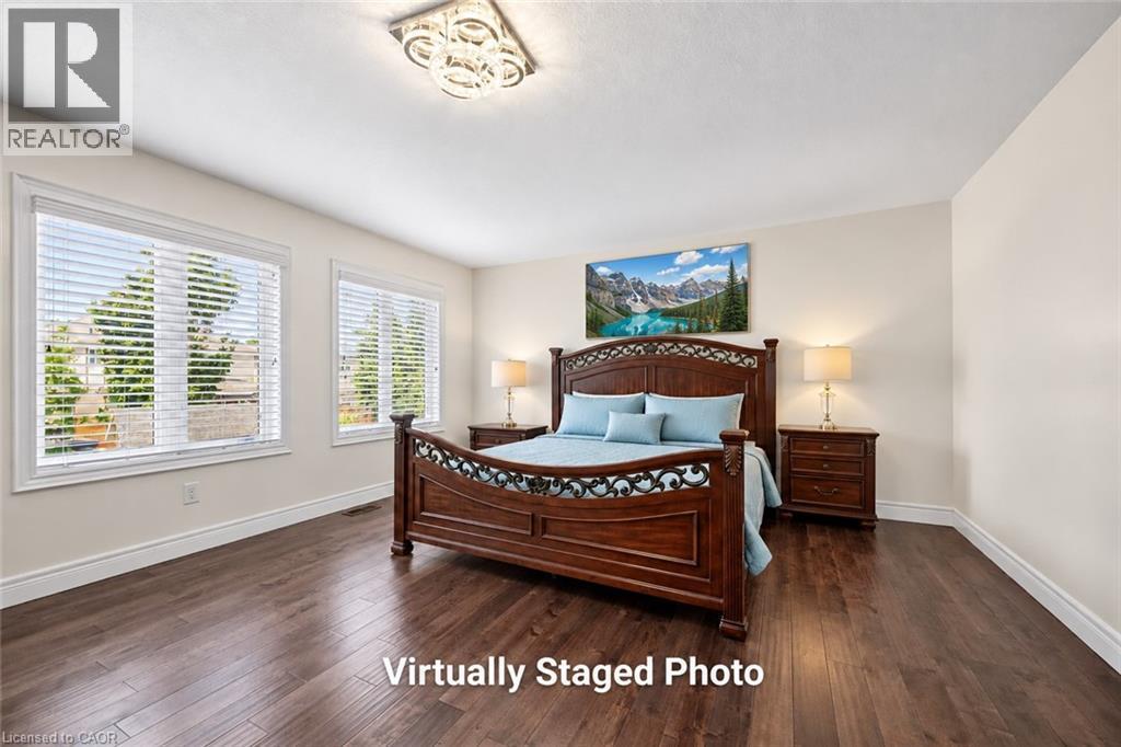 Spacious room featuring rich wood-finish flooring, light-toned walls, and a contemporary ceiling light fixture - 145 Redtail Street, Kitchener, ON - Indoor Photo Showing Bedroom