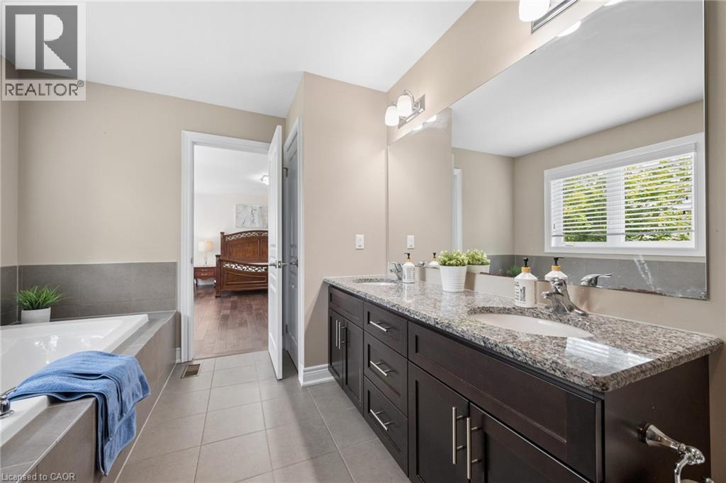Dual vanity with granite countertop, integrated sinks, and dark wood-finish cabinetry - 145 Redtail Street, Kitchener, ON - Indoor Photo Showing Bathroom