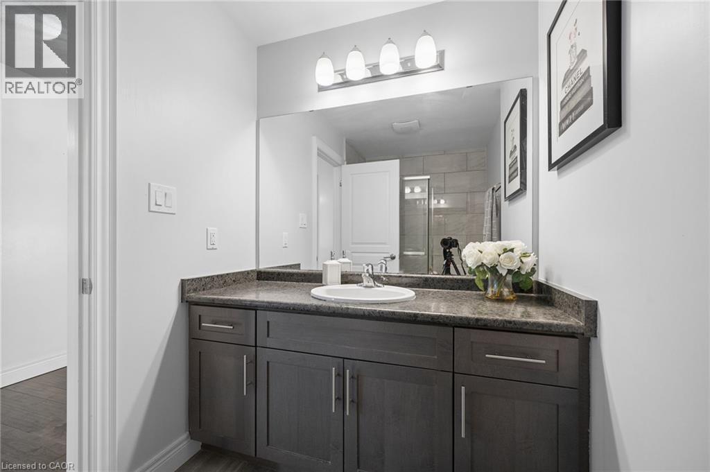 Bathroom vanity featuring a dark wood-finish cabinet, speckled countertop, and integrated sink - 145 Redtail Street, Kitchener, ON - Indoor Photo Showing Bathroom