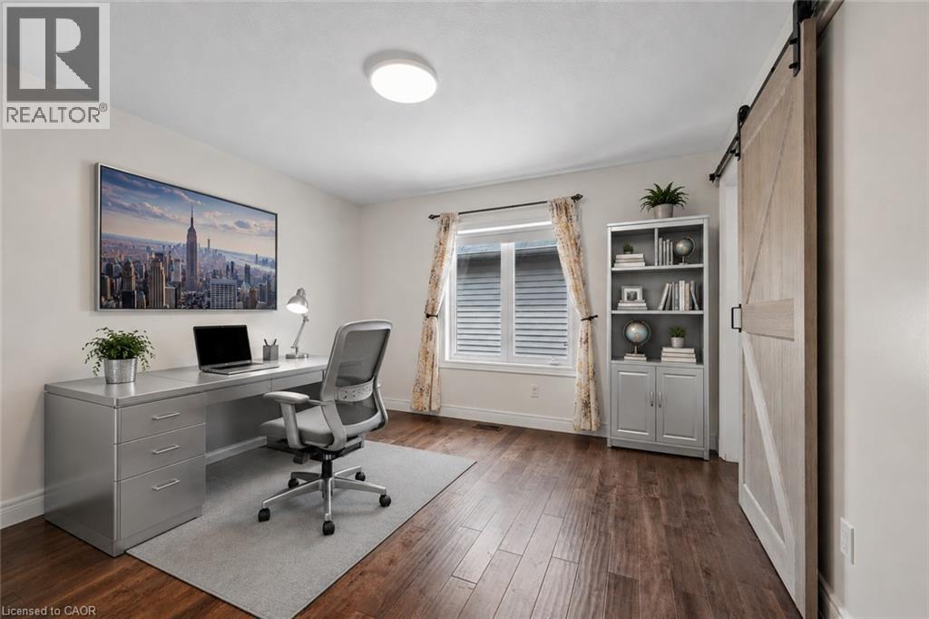 Dedicated office space featuring wood-finish flooring, a contemporary sliding barn door, and a built-in bookshelf - 145 Redtail Street, Kitchener, ON - Indoor Photo Showing Office