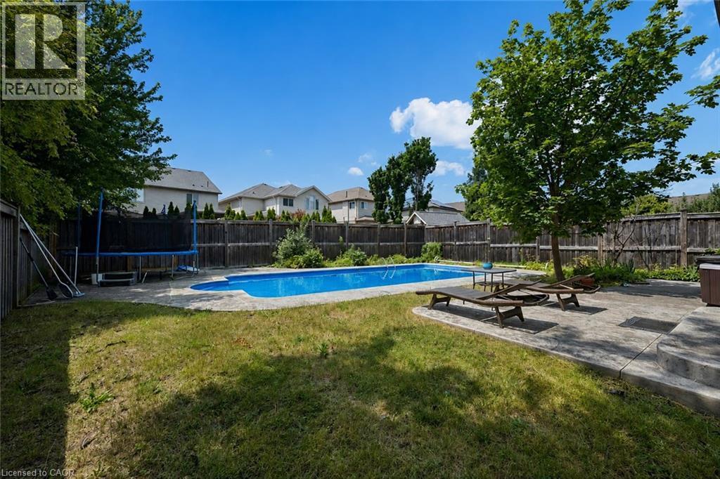 Expansive backyard featuring an in-ground swimming pool, stamped concrete patio, and a privacy fence - 145 Redtail Street, Kitchener, ON - Outdoor With In Ground Pool With Backyard