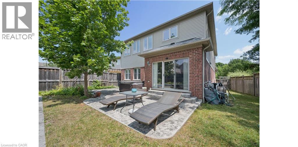 Rear exterior featuring brick and siding construction, sliding glass door, paver patio, and mature tree - 145 Redtail Street, Kitchener, ON - Outdoor With Deck Patio Veranda