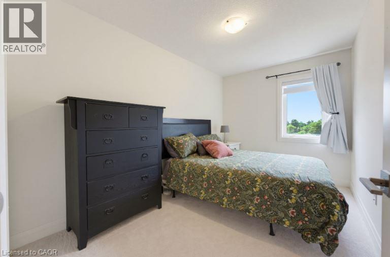 Bedroom featuring light-colored walls, ceiling-mounted light fixture, white window trim, and light-colored carpeting - 16 Raspberry Lane, Hamilton, ON - Indoor Photo Showing Bedroom