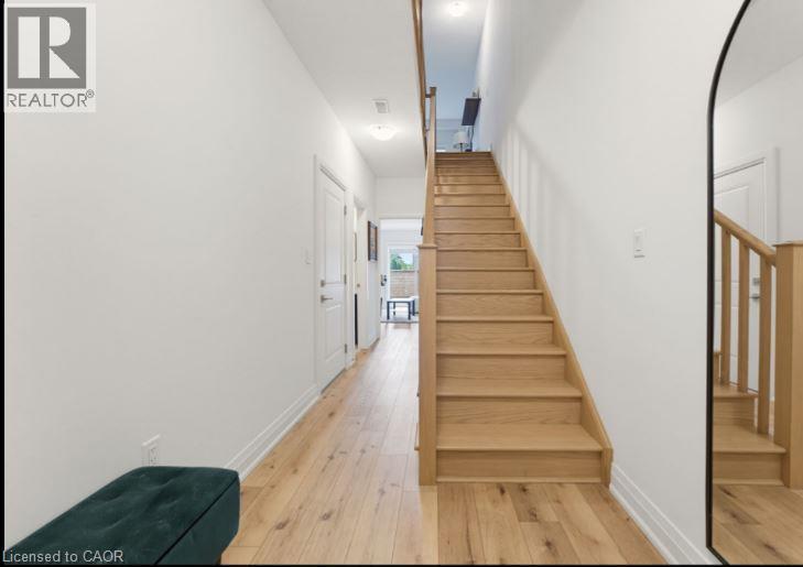 Inviting entryway featuring natural wood-finish flooring, a contemporary staircase with wood railings, white paneled doors, and recessed ceiling lighting - 16 Raspberry Lane, Hamilton, ON - Indoor Photo Showing Other Room