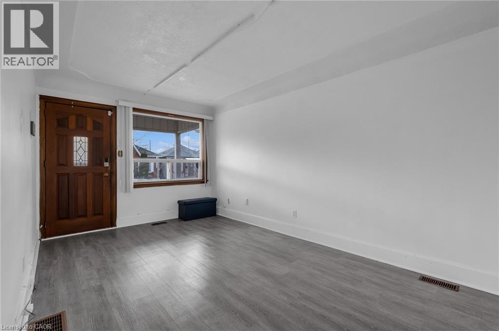 Foyer with wood-finish flooring, a paneled entry door with decorative glass, and a large front-facing window - 29 Harrison Avenue, Hamilton, ON - Indoor Photo Showing Other Room