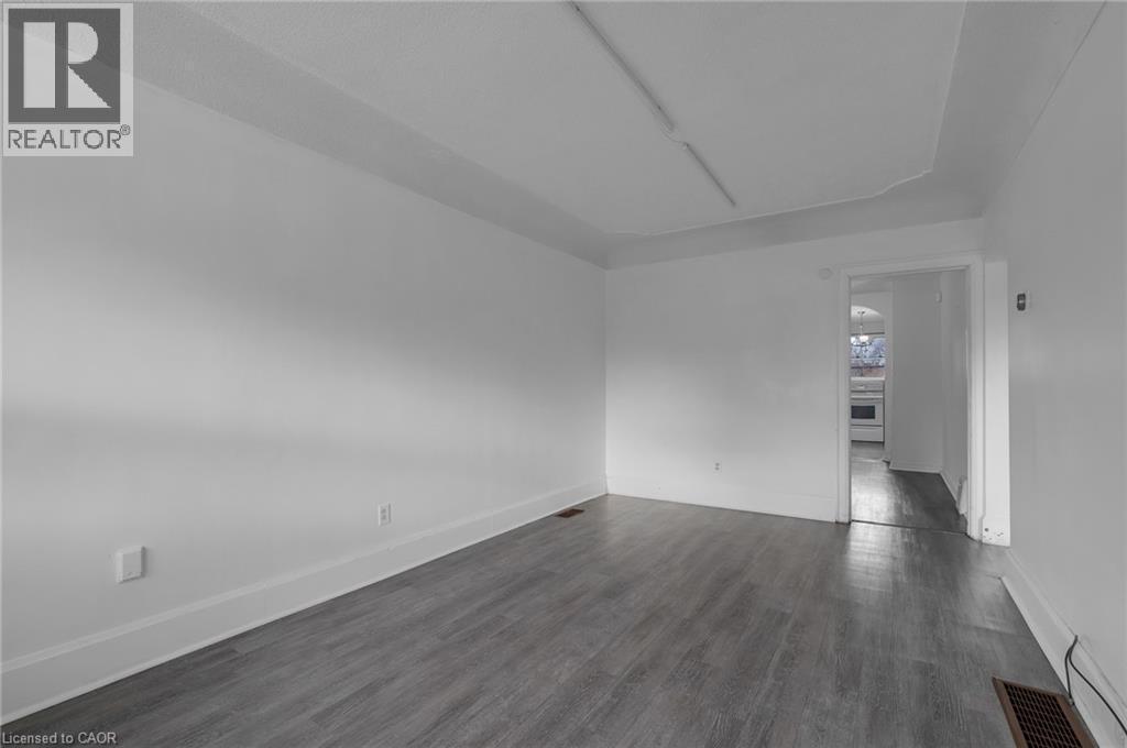 Spacious room featuring light gray wood-finish flooring, white walls, and white trim - 29 Harrison Avenue, Hamilton, ON - Indoor Photo Showing Other Room