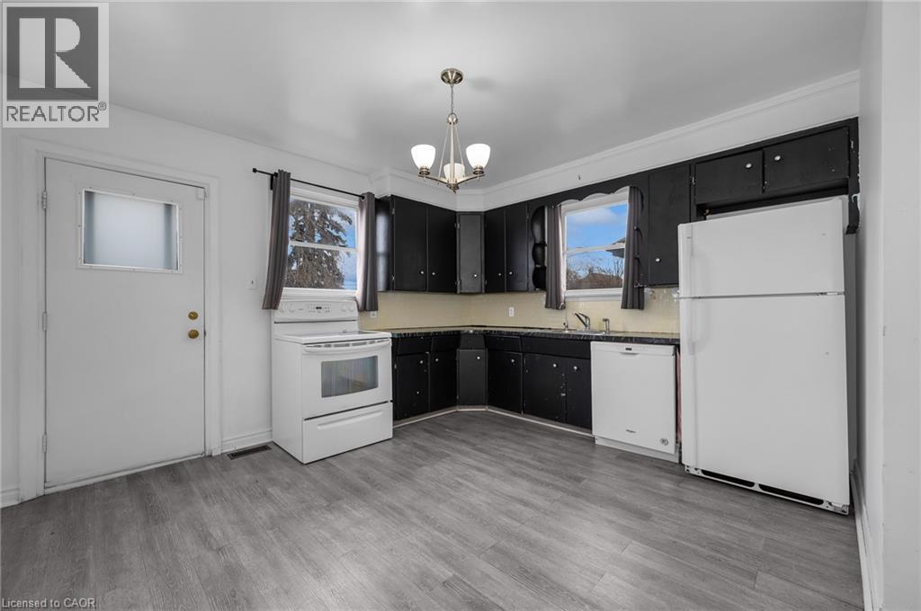 Kitchen featuring dark cabinetry with light countertops, a white refrigerator, and a white oven - 29 Harrison Avenue, Hamilton, ON - Indoor Photo Showing Kitchen
