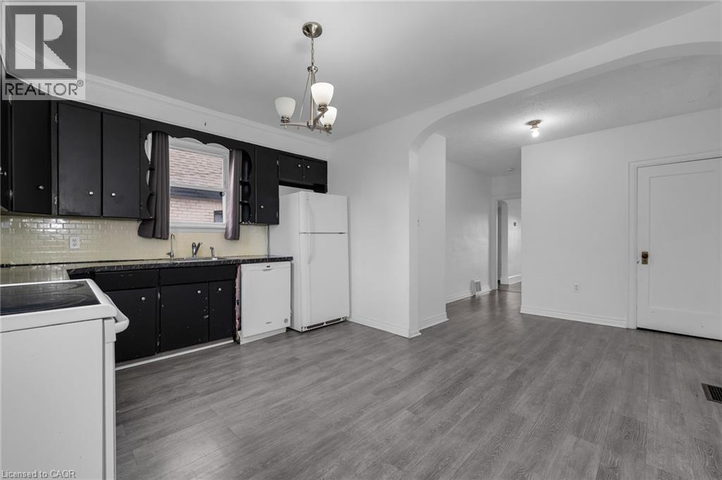 Kitchen featuring black cabinetry, a white subway tile backsplash, and dark countertops - 29 Harrison Avenue, Hamilton, ON - Indoor Photo Showing Kitchen