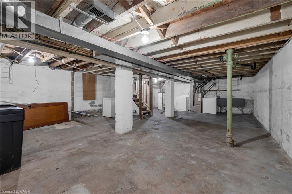 Unfinished basement featuring exposed wood joists, concrete flooring, concrete block walls, and utility hookups - 29 Harrison Avenue, Hamilton, ON - Indoor Photo Showing Basement
