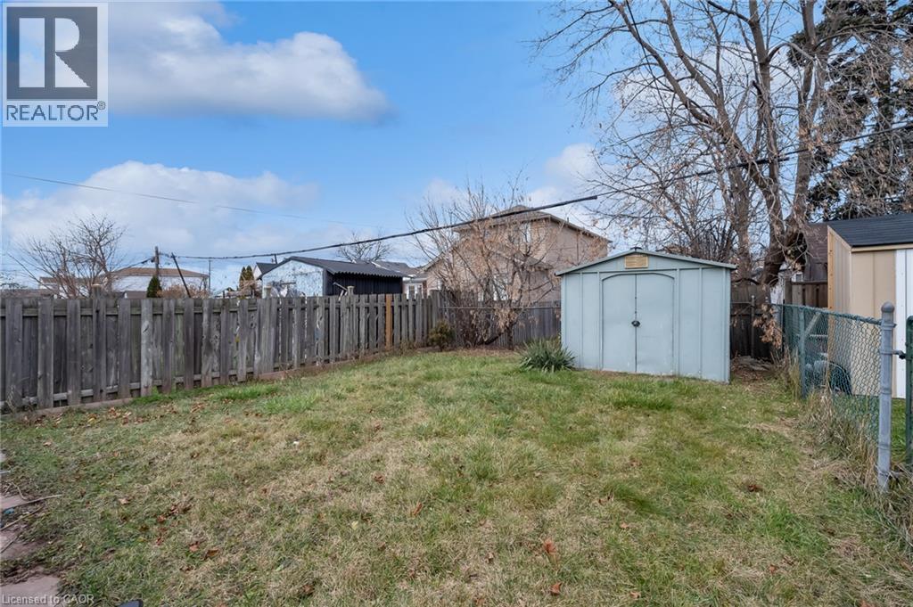 Expansive backyard featuring a metal storage shed, wood privacy fence, and chain-link fencing - 29 Harrison Avenue, Hamilton, ON - Outdoor