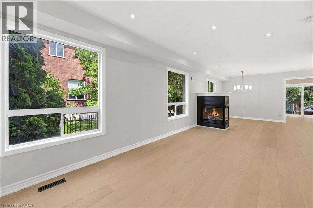 Expansive interior featuring light wood-finish flooring, recessed lighting, and a modern fireplace with a dark surround and light mantel - 5628 Stella Lane, Burlington, ON - Indoor Photo Showing Living Room With Fireplace