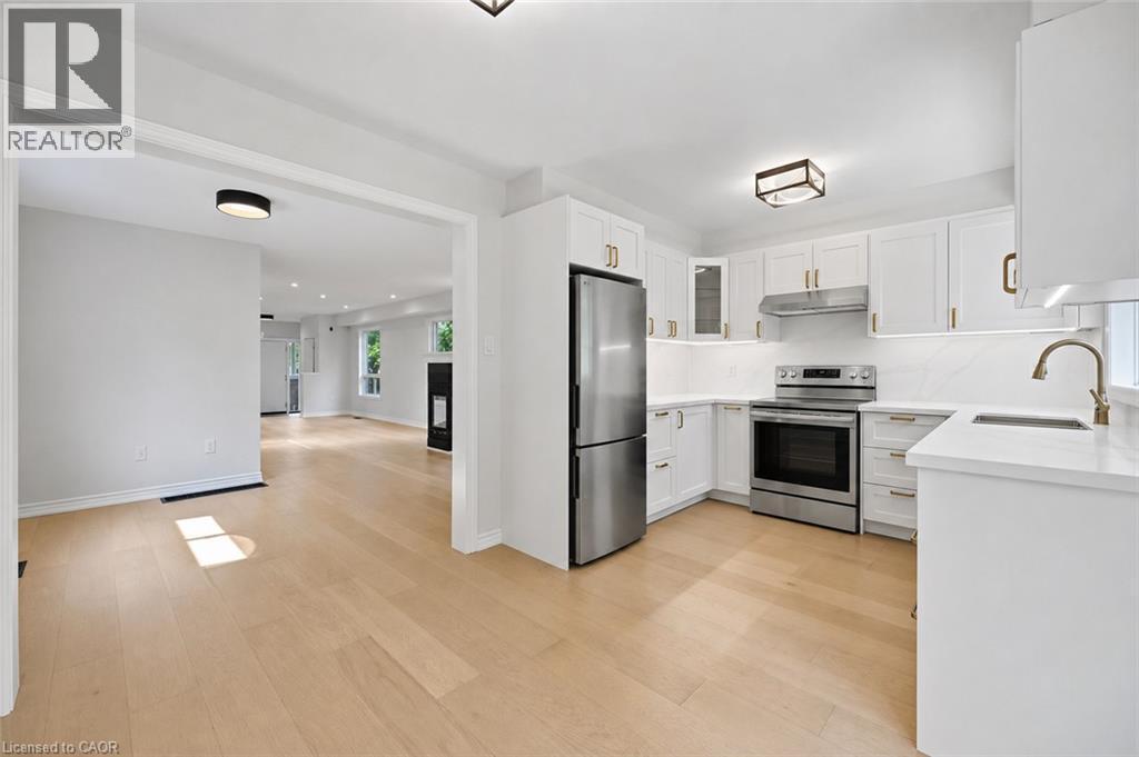 Modern kitchen featuring white cabinetry, stainless steel appliances, light countertops, and wood-finish flooring - 5628 Stella Lane, Burlington, ON - Indoor Photo Showing Kitchen