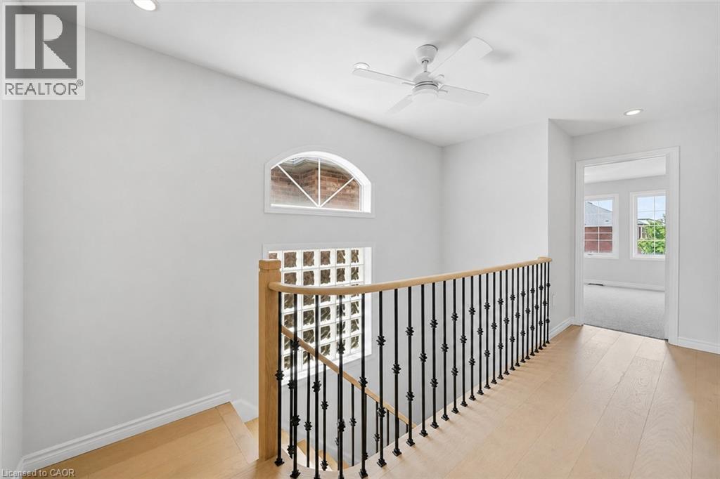 Upper-level landing featuring wood-finish flooring, a white ceiling fan, recessed lighting, an arched window, and a wrought iron and wood staircase railing - 5628 Stella Lane, Burlington, ON - Indoor Photo Showing Other Room