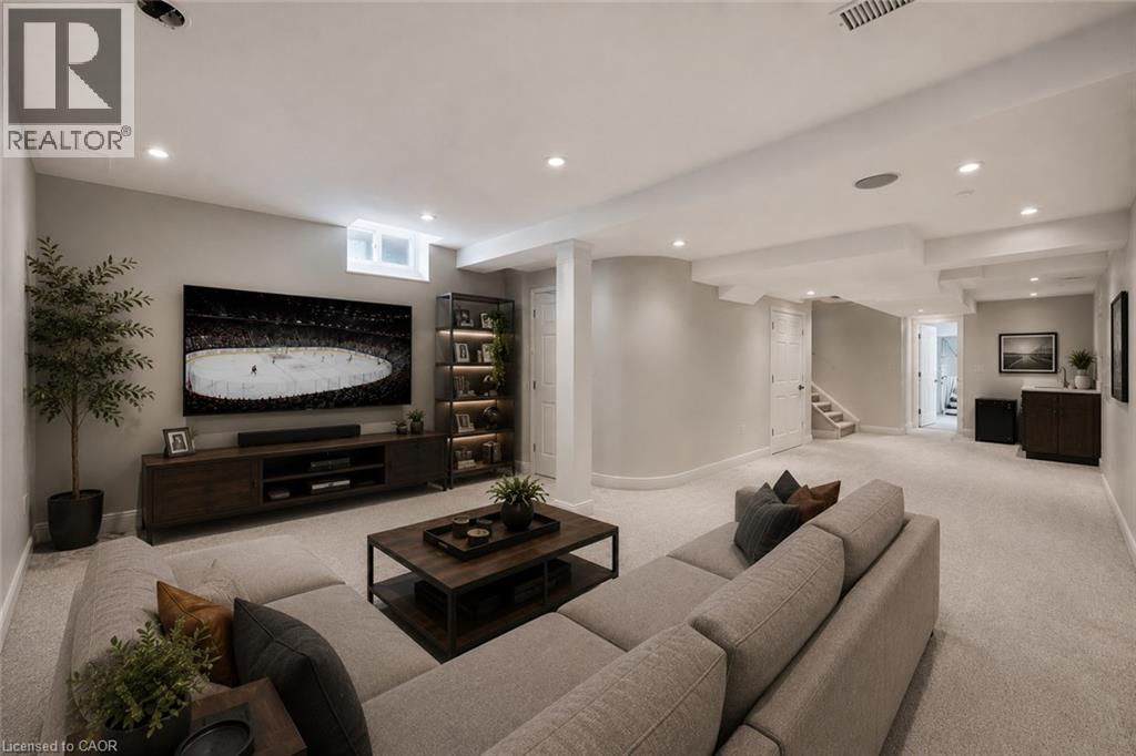 Spacious recreation area featuring plush carpeting, recessed lighting, a built-in media console, an illuminated display shelf, and a wet bar with a dark wood-finish cabinet - 5628 Stella Lane, Burlington, ON - Indoor