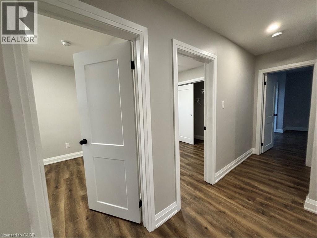 Hallway featuring wood-finish flooring, light grey painted walls, white trim, recessed lighting, and white paneled doors with dark hardware - 773 Lawrence Road, Hamilton, ON - Indoor Photo Showing Other Room