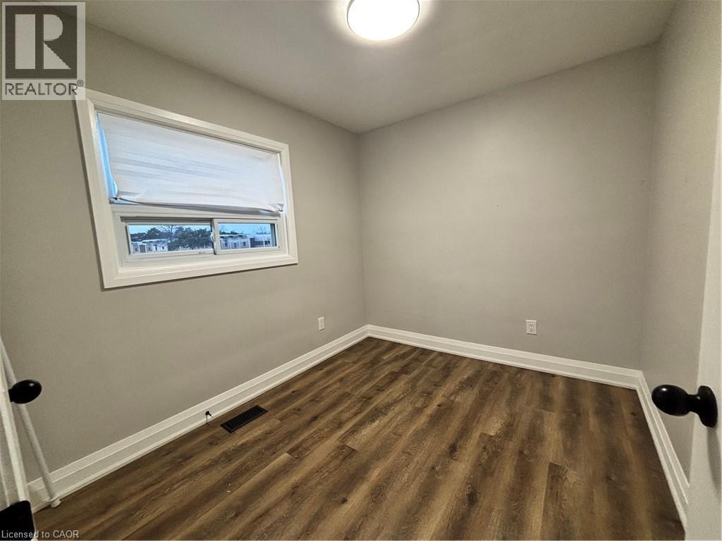 Neutral wall paint, wood-finish flooring, and white baseboards provide a clean aesthetic - 773 Lawrence Road, Hamilton, ON - Indoor Photo Showing Other Room
