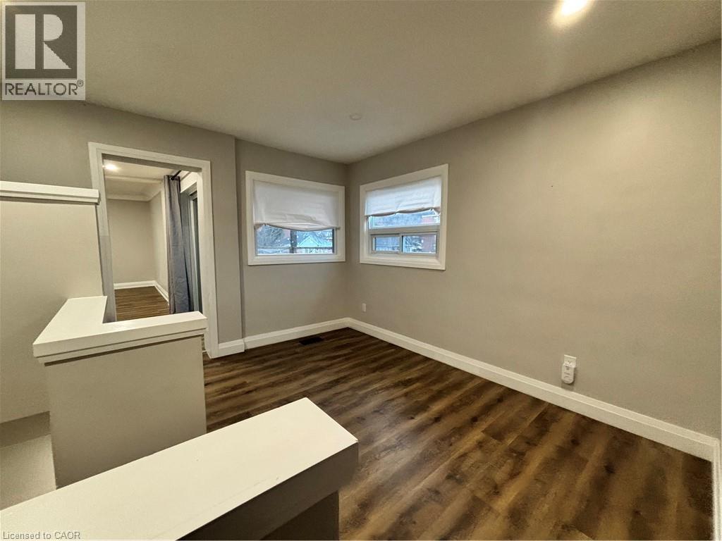 Upper-level room featuring wood-finish flooring, two windows with blinds, and light neutral wall paint - 773 Lawrence Road, Hamilton, ON - Indoor Photo Showing Other Room