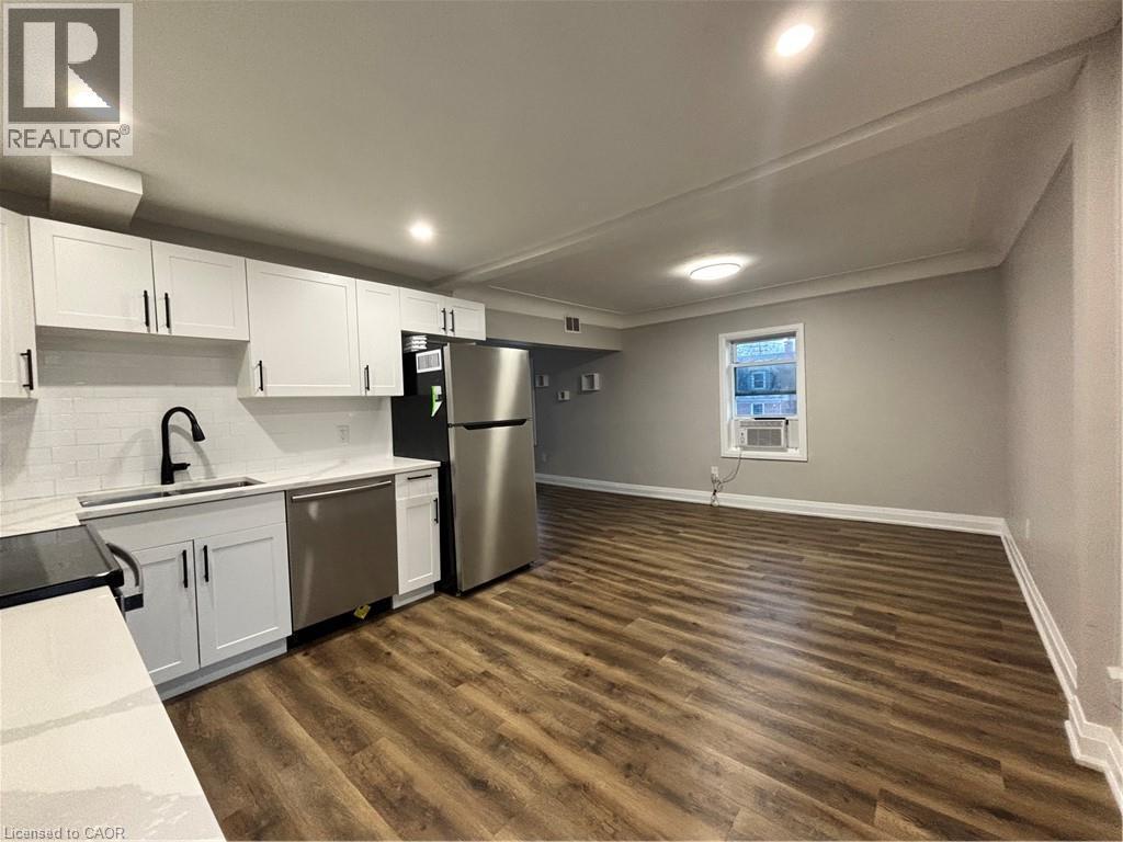 Open-concept living space featuring a modern kitchen with white shaker-style cabinetry, quartz countertops, and stainless steel appliances - 773 Lawrence Road, Hamilton, ON - Indoor Photo Showing Kitchen