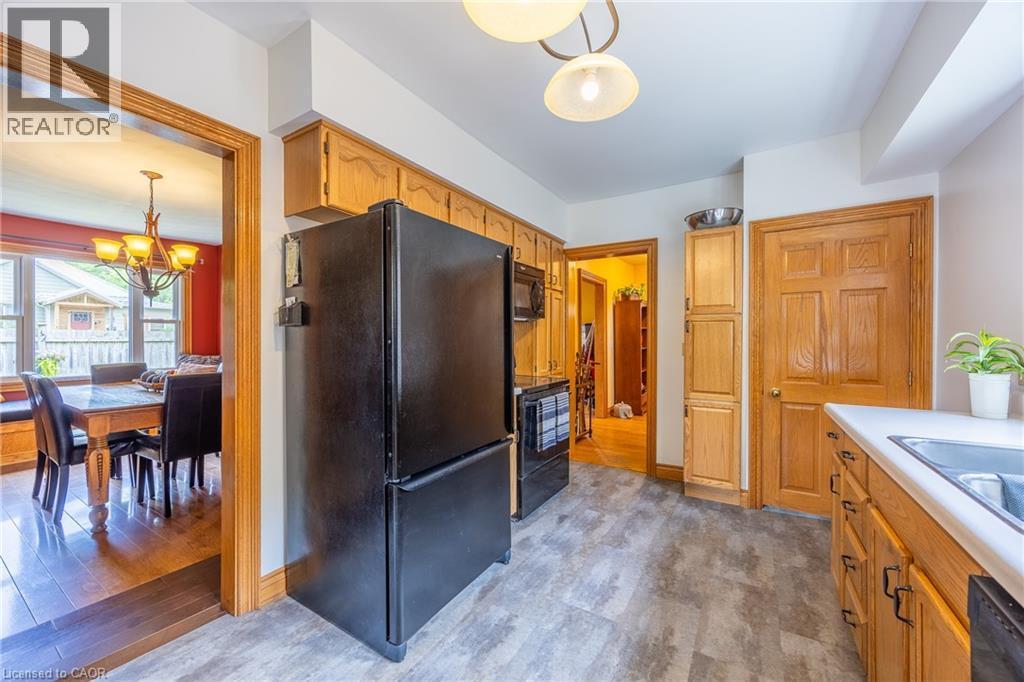 Kitchen with wood-finish cabinetry, black appliances, and durable gray flooring - 5 Hawthorne Avenue, Simcoe, ON - Indoor