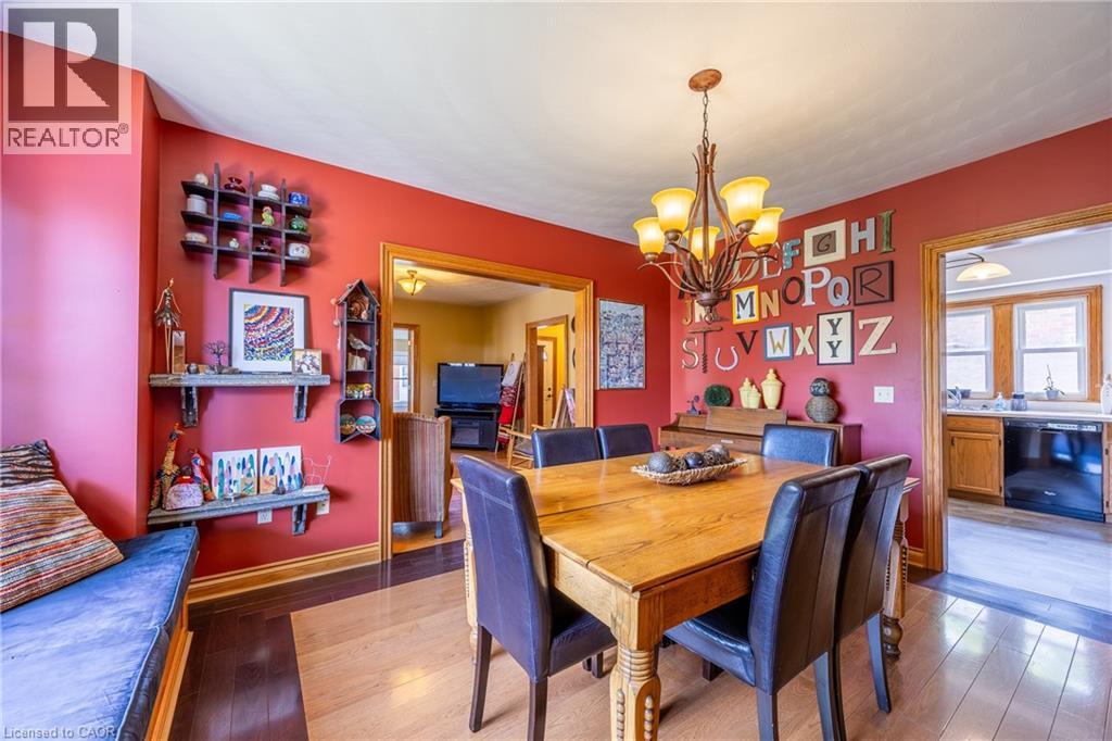 Dining area featuring red walls and a multi-tone wood-finish floor - 5 Hawthorne Avenue, Simcoe, ON - Indoor Photo Showing Dining Room