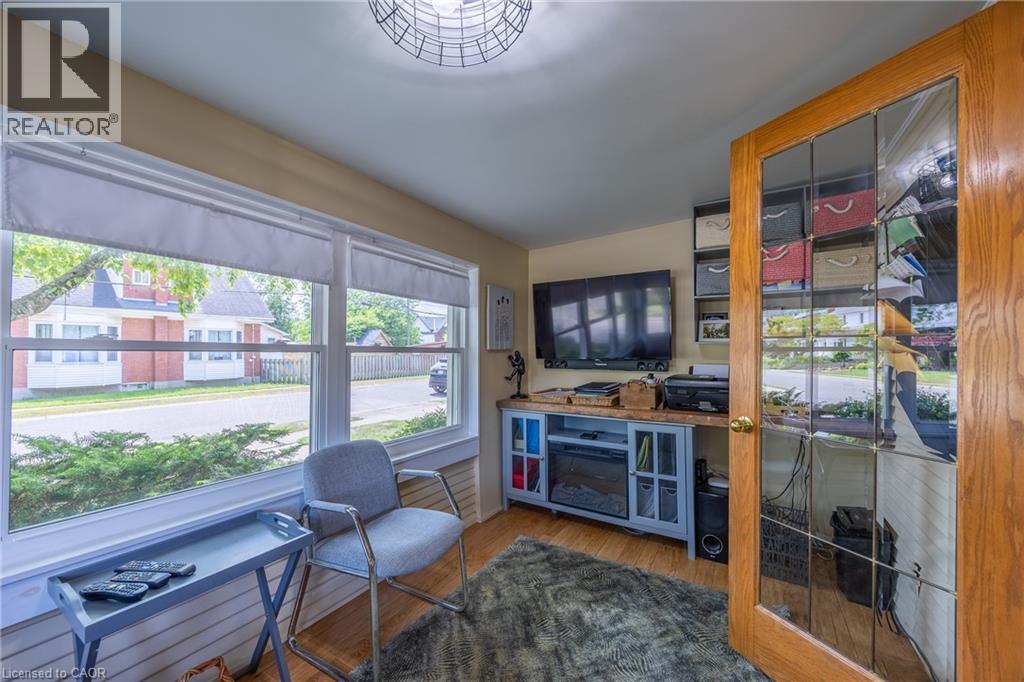 Room featuring large windows with privacy shades, wood-finish flooring, and a decorative light fixture - 5 Hawthorne Avenue, Simcoe, ON - Indoor