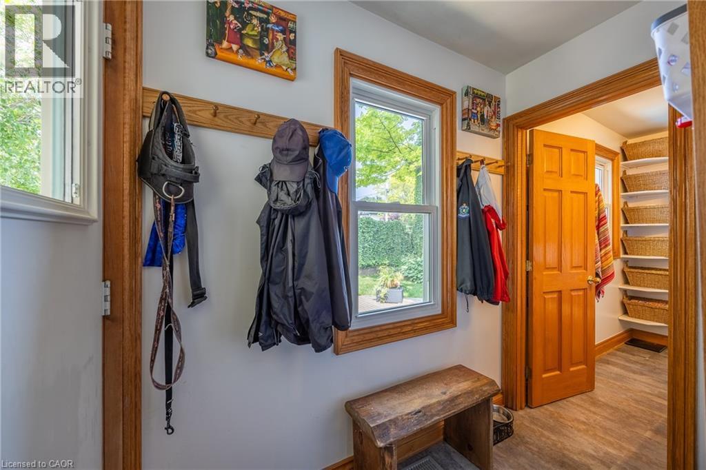 Entryway featuring wood-finish flooring, a window overlooking exterior greenery, wood trim, a built-in coat rack, and an adjacent storage area with built-in shelving - 5 Hawthorne Avenue, Simcoe, ON - Indoor