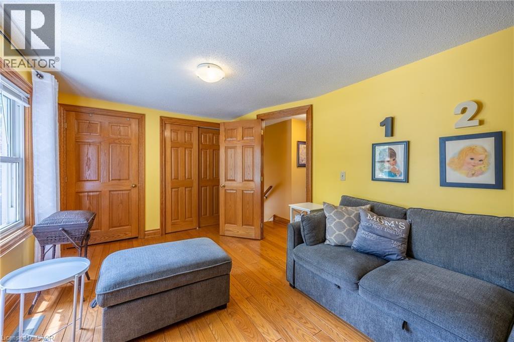 Room featuring wood-finish flooring, natural wood doors, and a ceiling-mounted light fixture - 5 Hawthorne Avenue, Simcoe, ON - Indoor Photo Showing Living Room