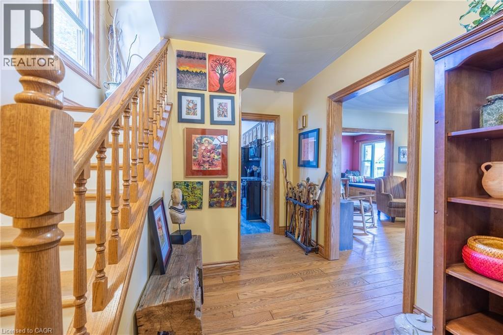 Hardwood flooring extends throughout the entryway, featuring a solid wood staircase with turned balusters and a substantial newel post - 5 Hawthorne Avenue, Simcoe, ON - Indoor Photo Showing Other Room