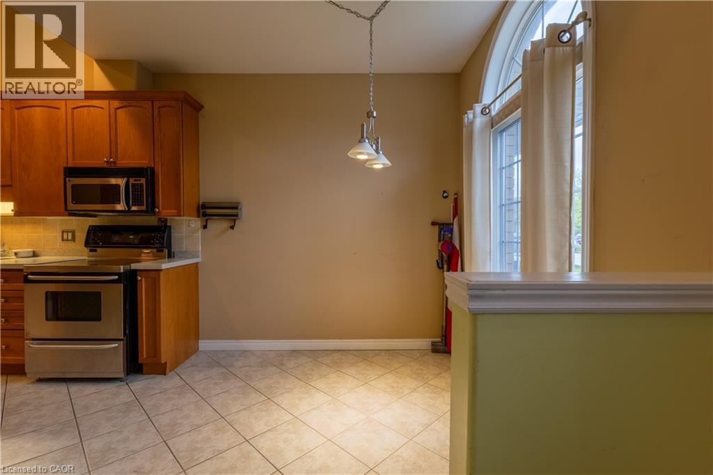 Kitchen area featuring wood cabinetry, stainless steel appliances, and tiled flooring - 4066 Medland Drive, Burlington, ON - Indoor Photo Showing Kitchen