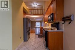 Kitchen featuring tile flooring, wood cabinetry, stainless steel appliances, light-toned countertops, and a tile backsplash -