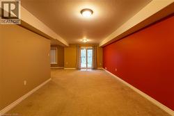 Lower level featuring a corner fireplace with a wood-finish mantel, carpet flooring, and a large window with blinds -
