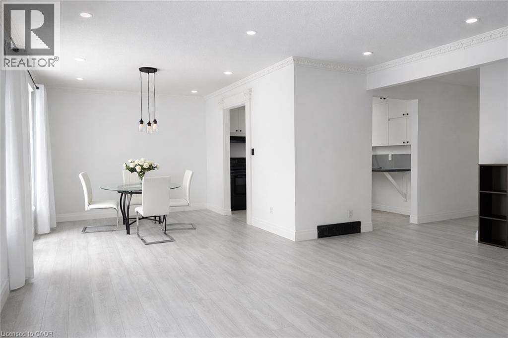 Open-concept living space featuring light wood-finish flooring, recessed lighting, and crown molding - 84 Elgar Avenue, Hamilton, ON