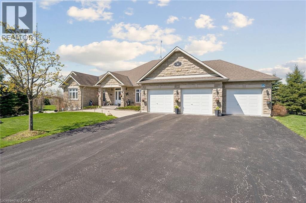 Stone facade residence featuring a three-car garage, asphalt driveway, and a covered portico entrance - 10 Brolley Crescent, Thornton, ON - Outdoor With Facade