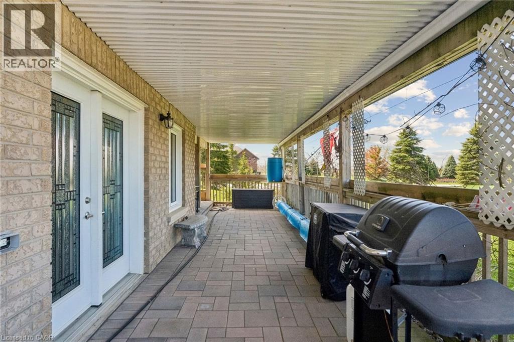 Covered brick patio featuring paver stone flooring, a full-length overhead ceiling, and white lattice accents - 10 Brolley Crescent, Thornton, ON - Outdoor With Deck Patio Veranda With Exterior