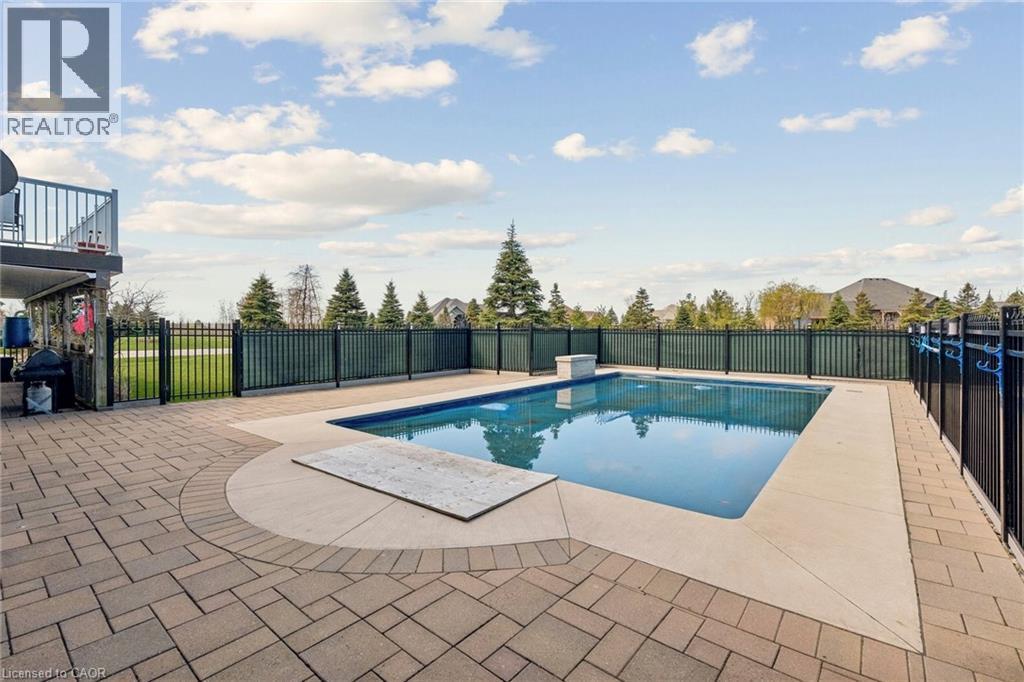 Rectangular swimming pool with a stone coping and surrounding paver patio - 10 Brolley Crescent, Thornton, ON - Outdoor With In Ground Pool